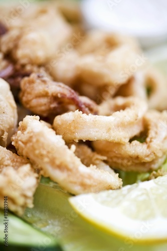 Deep-fried squid rings with wedge of lemon photo