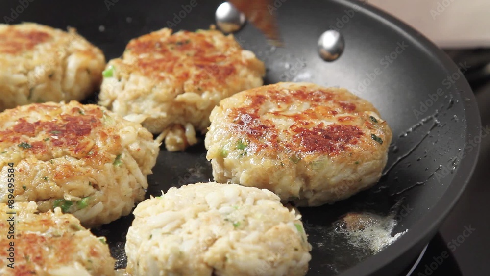 Crab cakes being fried in a pan