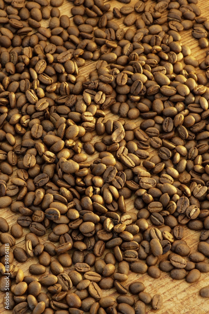 Lots of coffee beans on a wooden surface Lots of coffee beans on a wooden surface