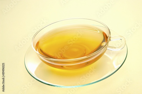 A glass teacup of yellow tea
