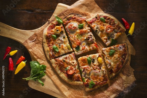 A Veggie Pizza with Fresh Basil Sliced on a Pizza Board; From Above