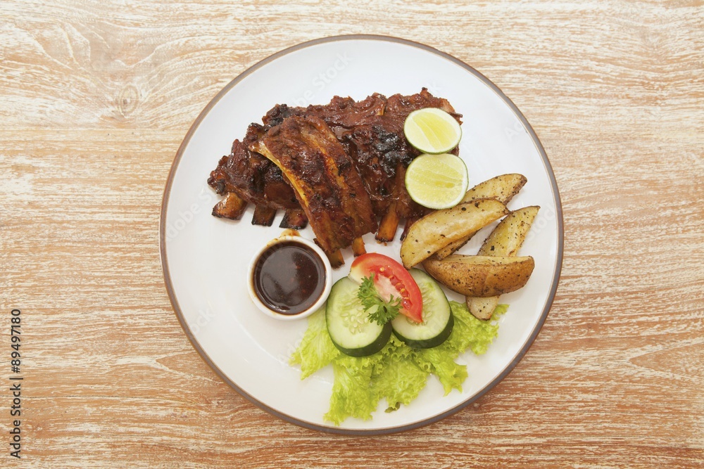 Spare ribs with potato wedges, barbecue sauce and a side salad