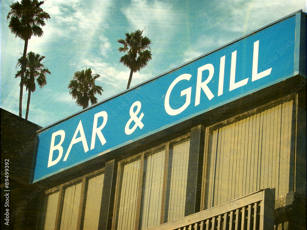 aged and worn vintage photo of bar and grill sign and palm trees