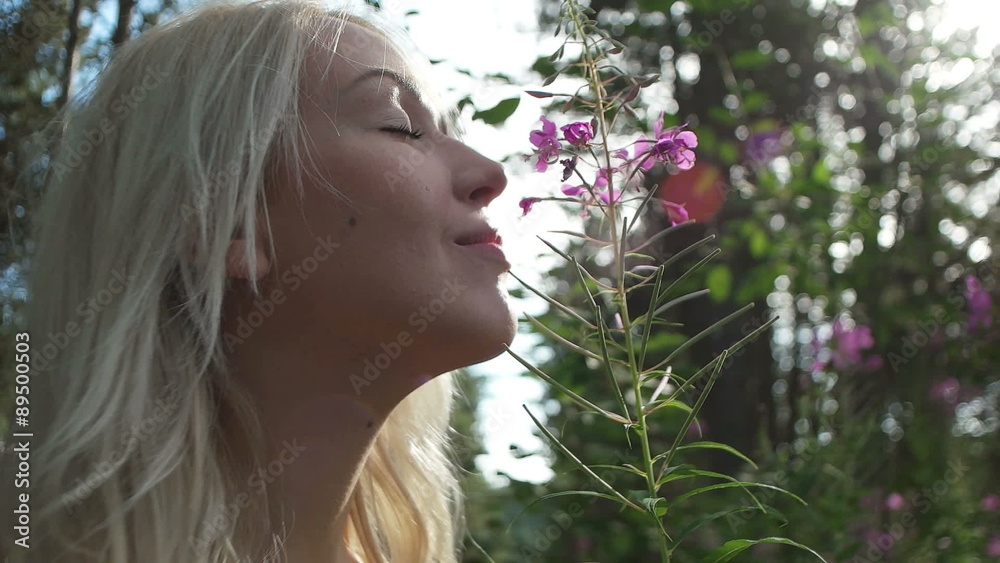 Beautiful blonde girl in nature enjoying the sun, girl smelling the flowers Beautiful blonde girl in nature enjoying the sun, girl smelling the flowers