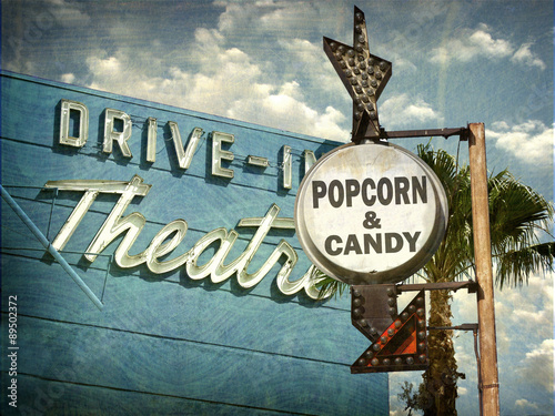 aged and worn vintage photo of drive in movies sign with popcorn and candy advertisement photo