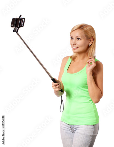 Young woman taking selfie photo with stick isolated on white