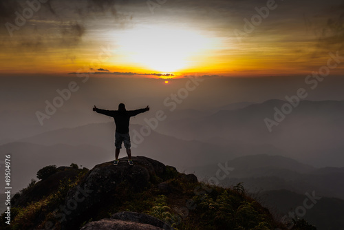 Hiker open arms on peak of mountain at sunset. © Eakkaluk