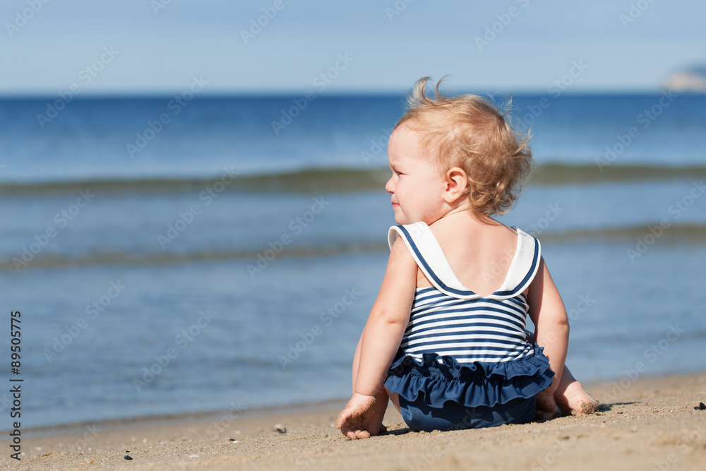Little girl sitting on beach in swimsuit and dreams Little girl sitting on beach in swimsuit and dreams