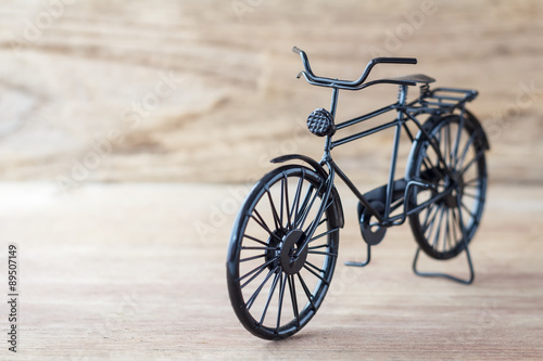 Vintage model black bicycle on old wooden table.