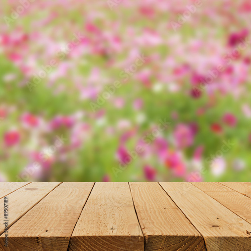 Defocus and blur image of terrace wood with flower field for bac