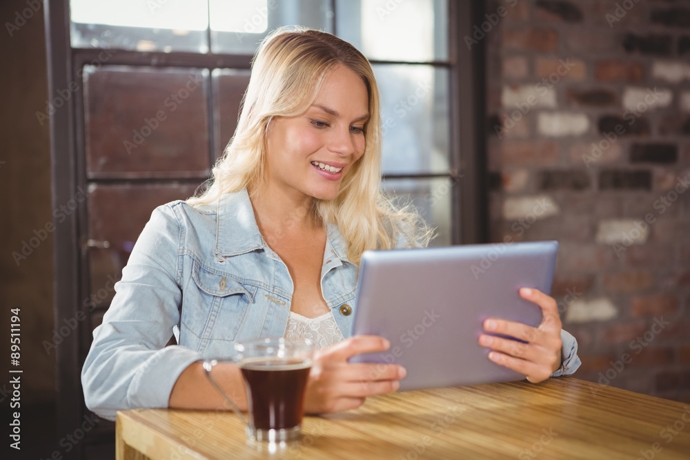 Smiling blonde having coffee and using tablet computer Smiling blonde having coffee and using tablet computer