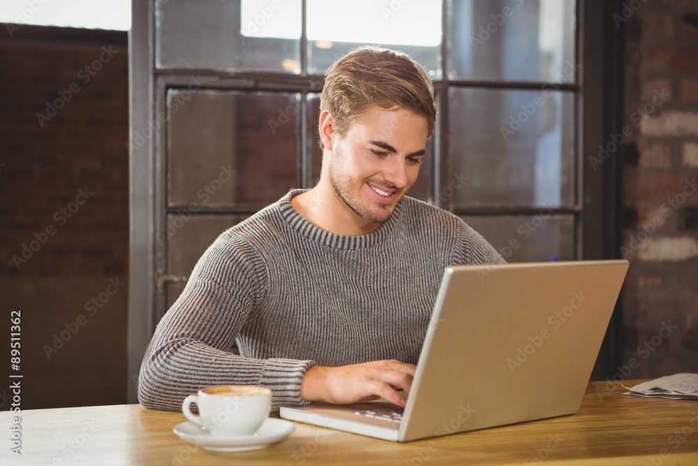 Handsome man smiling and typing on laptop Handsome man smiling and typing on laptop