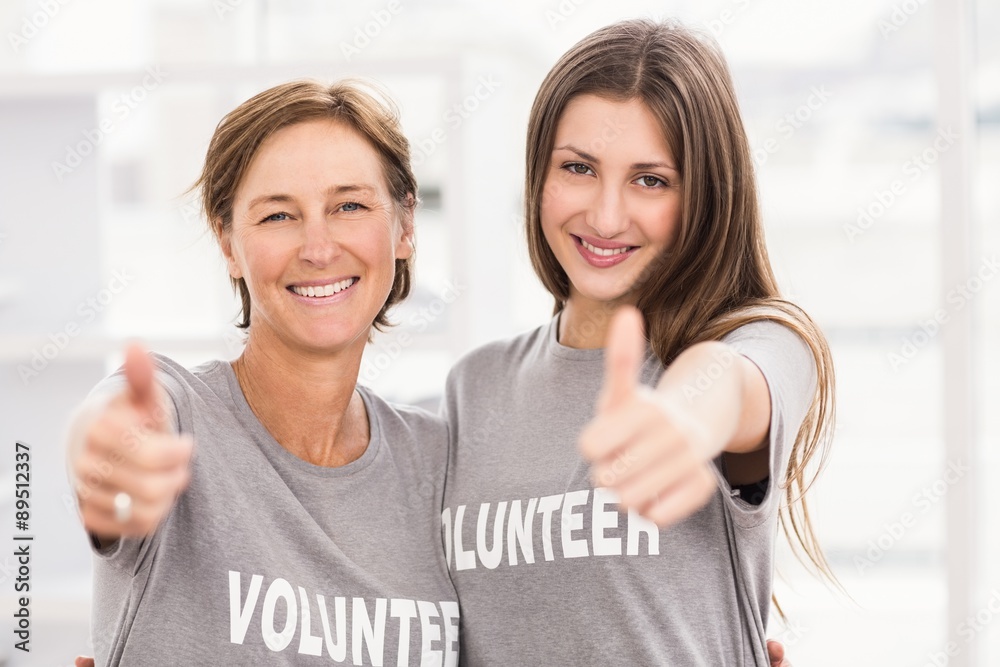 Fototapeta premium Smiling female volunteers doing thumbs up