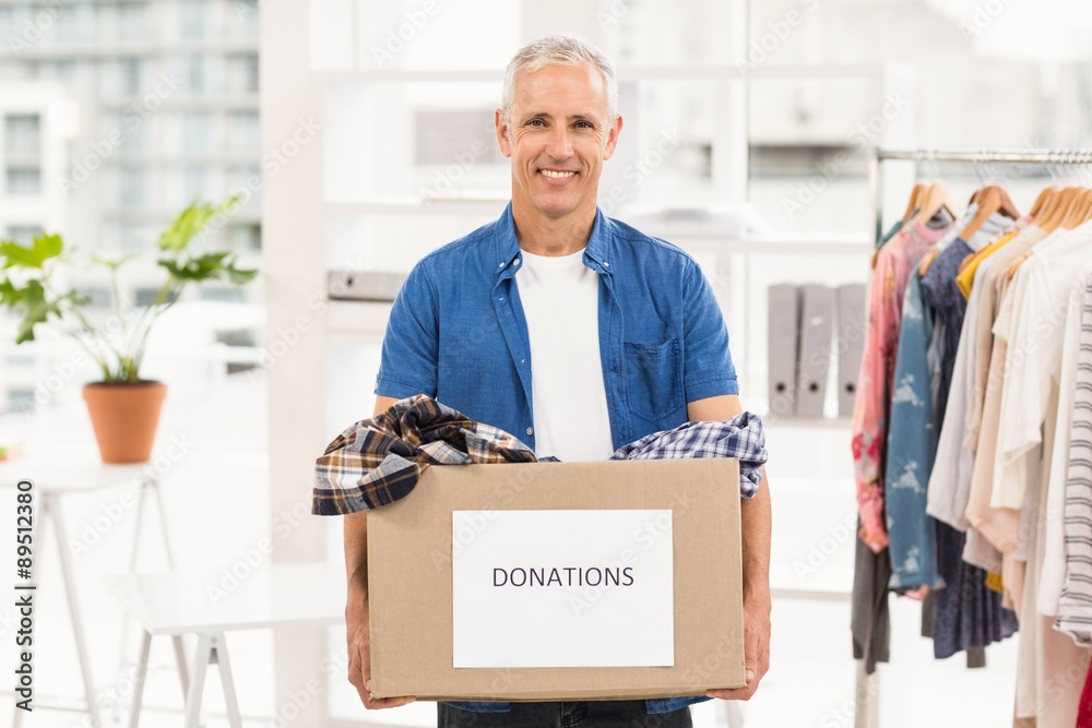 Smiling casual businessman holding donation box Smiling casual businessman holding donation box