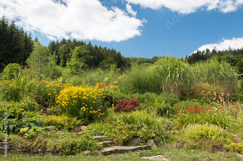 beautiful country garden with many blooming flowers and stone stairs