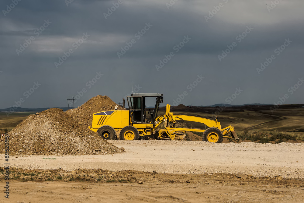 Obraz premium Grader leveling gravel on road construction site