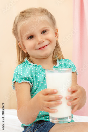 Cheerful little girl with glass of milk