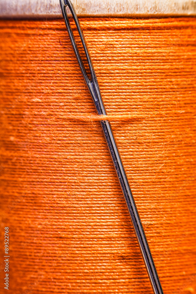 Spool of yellow thread with a needle stuck in it. Spool of yellow thread with a needle stuck in it.