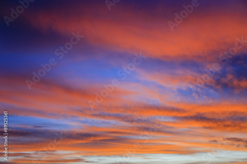 Fiery September evening skyscape with clouds lit by red sunset against a dark blue sky. UK Britain