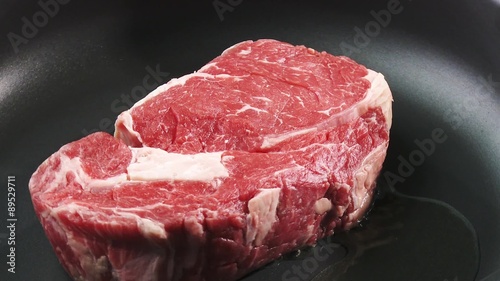Frying rib eye steak in a frying pan