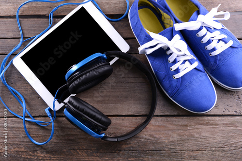 Headphones with sneakers and tablet on wooden background