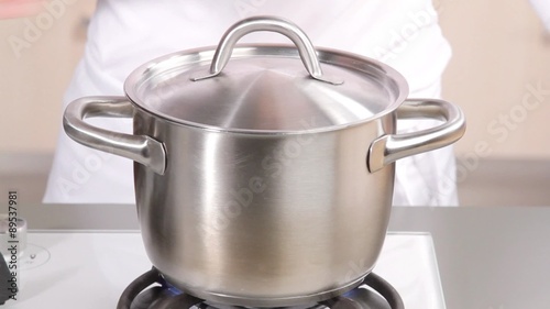 Switching on hob and placing lid on pan