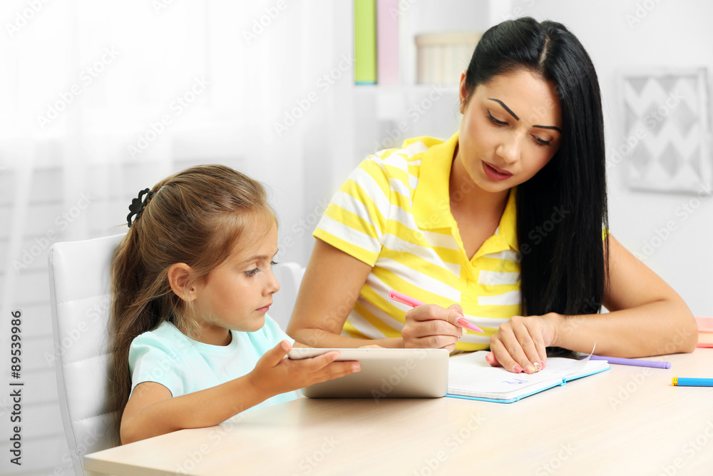 Beautiful school girl doing homework with mother at home Beautiful school girl doing homework with mother at home