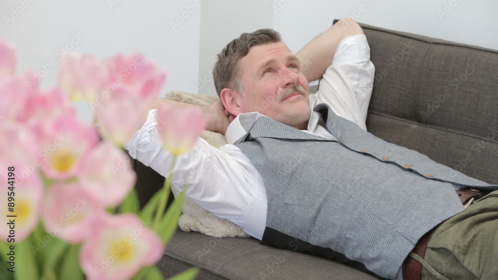 man lying on couch and looks very happy and satisfied man lying on couch and looks very happy and satisfied