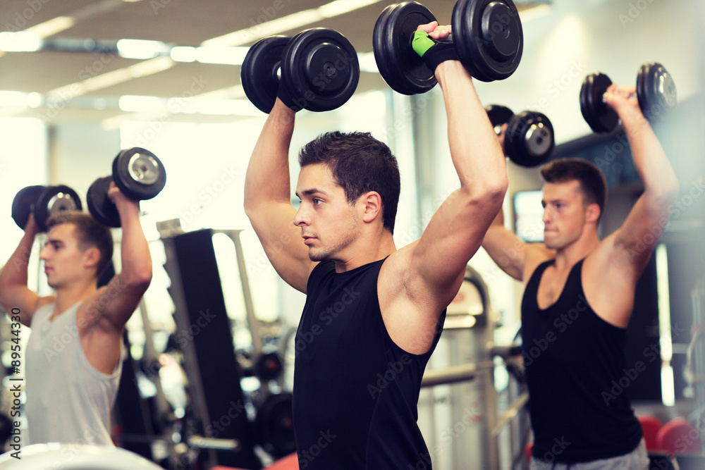 group of men with dumbbells in gym group of men with dumbbells in gym