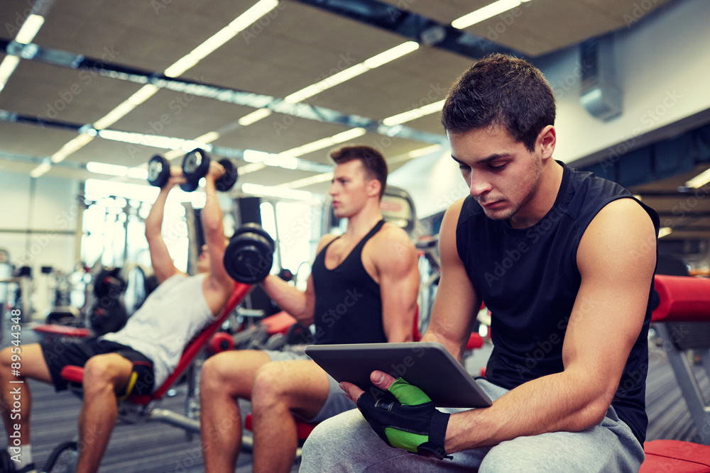 group of men with tablet pc and dumbbells in gym