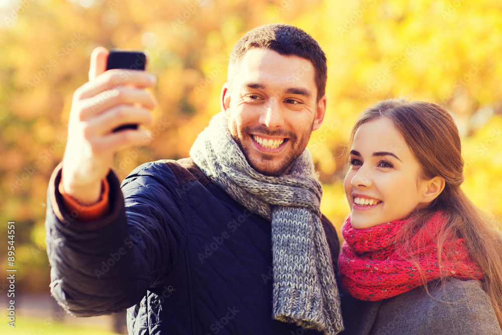 smiling couple with smartphone in autumn park smiling couple with smartphone in autumn park