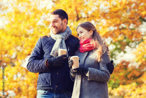 smiling couple with coffee cups in autumn park