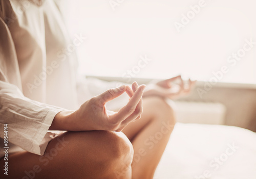 Woman meditating in the lotus position closeup. Beautiful girl doing exercises at home. Harmony, balance, meditation, relaxation, healthy lifestyle, mindfulness concept