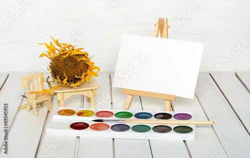 dried sunflower, easel and paints photo