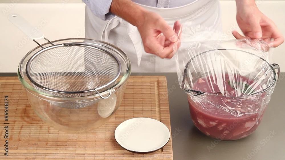 Veal in a red wine marinade being drained and the marinade being retained Veal in a red wine marinade being drained and the marinade being retained