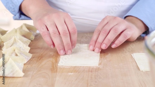 Won ton sheets being filled with a pork and prawn mixture photo