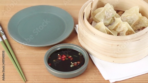 Dim sum in a bamboo basket and soy and chilli sauce photo