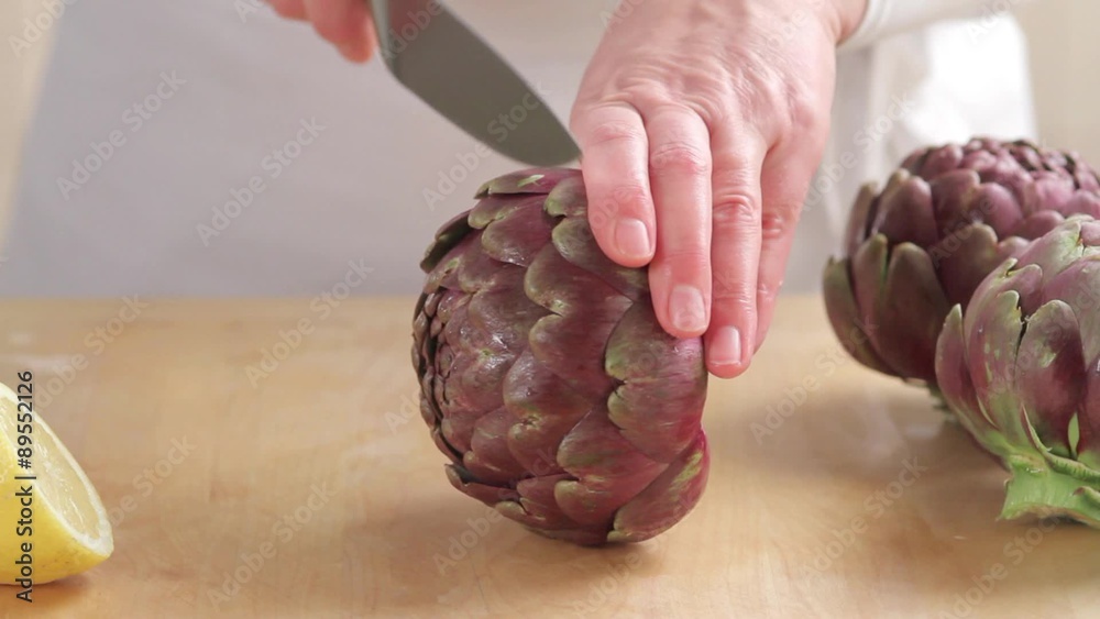 Removing leaf tips from artichokes and sprinkling the cut surface with
