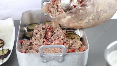 Moussaka being made: aubergine slices and minced meat being layered in a baking dish
