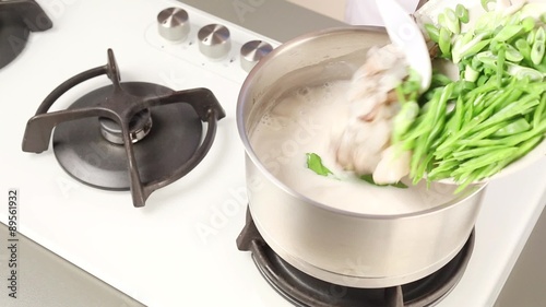 Prawns, mange tout and spring onions being added to coconut milk soup photo