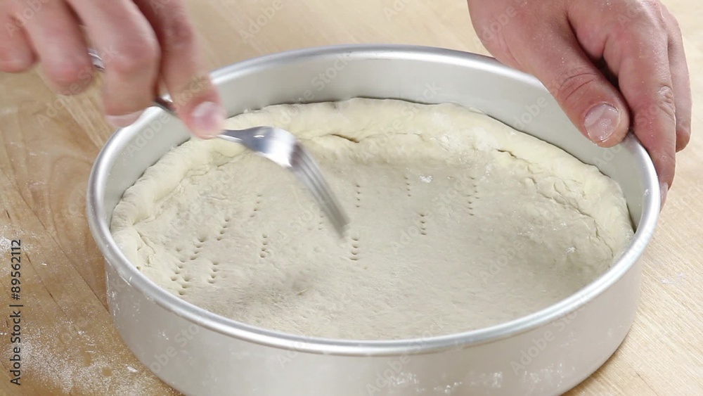 Pizza dough being pierced with a fork and brushed with olive oil Pizza dough being pierced with a fork and brushed with olive oil