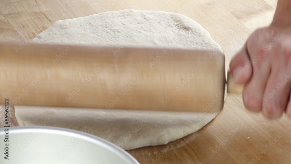 Pizza dough being rolled out and place in a deep pizza dish