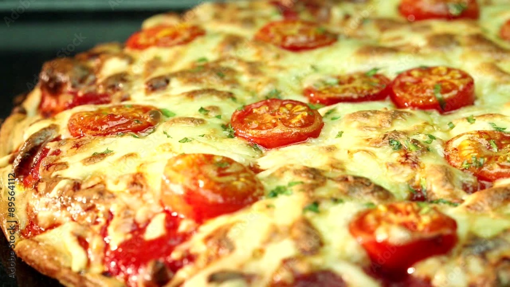 A pizza topped with mozzarella and cherry tomatoes, baking in the oven (close-up) A pizza topped with mozzarella and cherry tomatoes, baking in the oven (close-up)