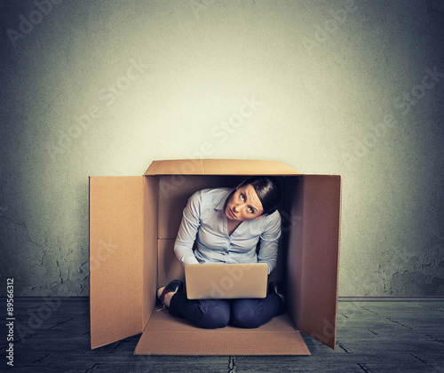 Businesswoman hiding in the box working on computer