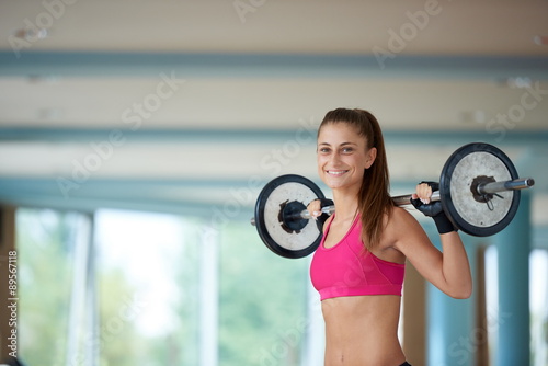 young woman in fitness gym lifting weights