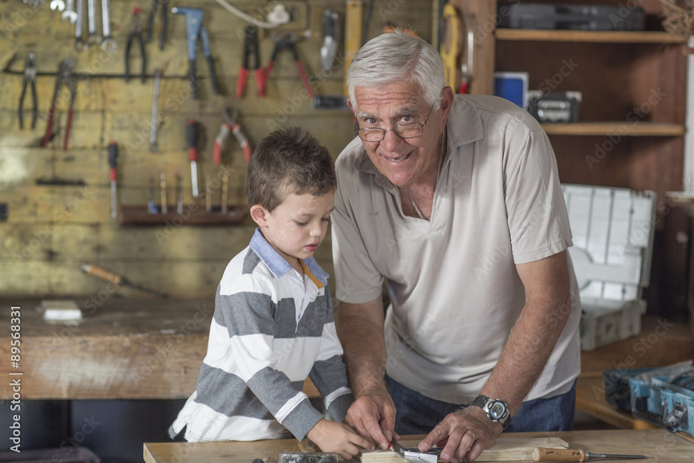Grandfather and grandson working with wood in a garage Grandfather and grandson working with wood in a garage