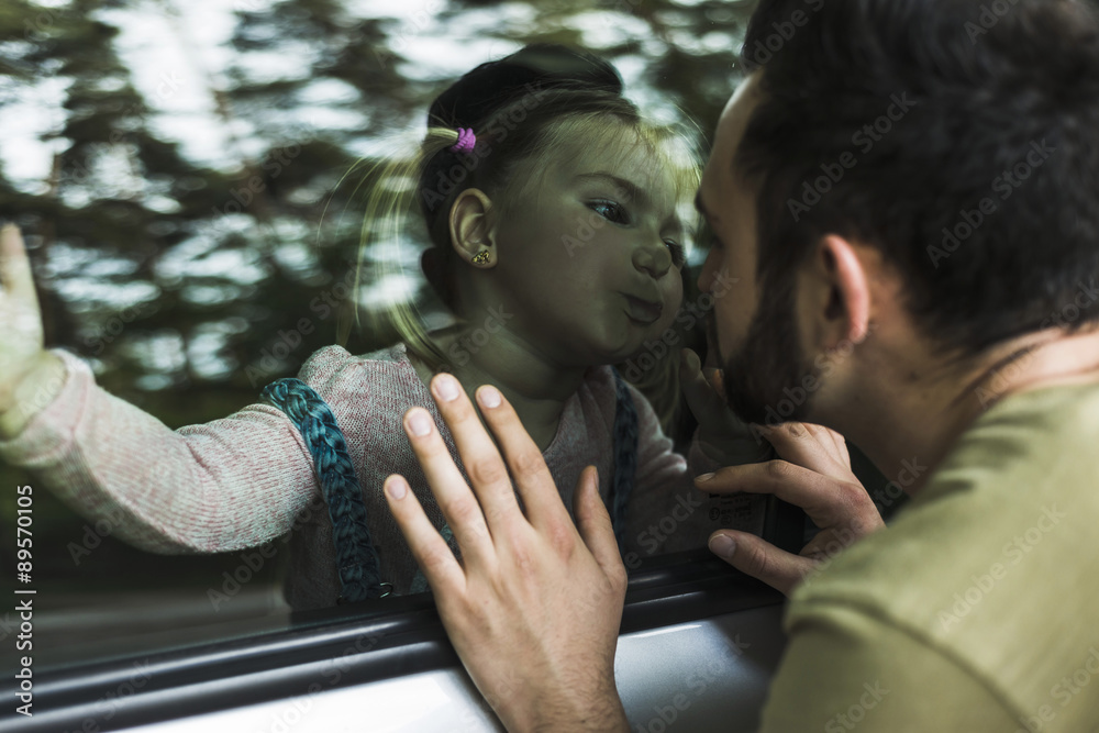 Girl in car kissing father behind window pane Girl in car kissing father behind window pane