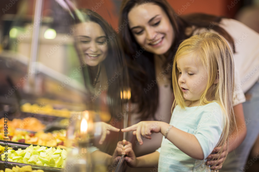 Mother and daughter looking at fruit salad in supermarket Mother and daughter looking at fruit salad in supermarket