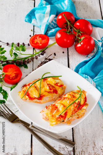 Chicken chops, fillet, baked with tomatoes and cheese on wooden