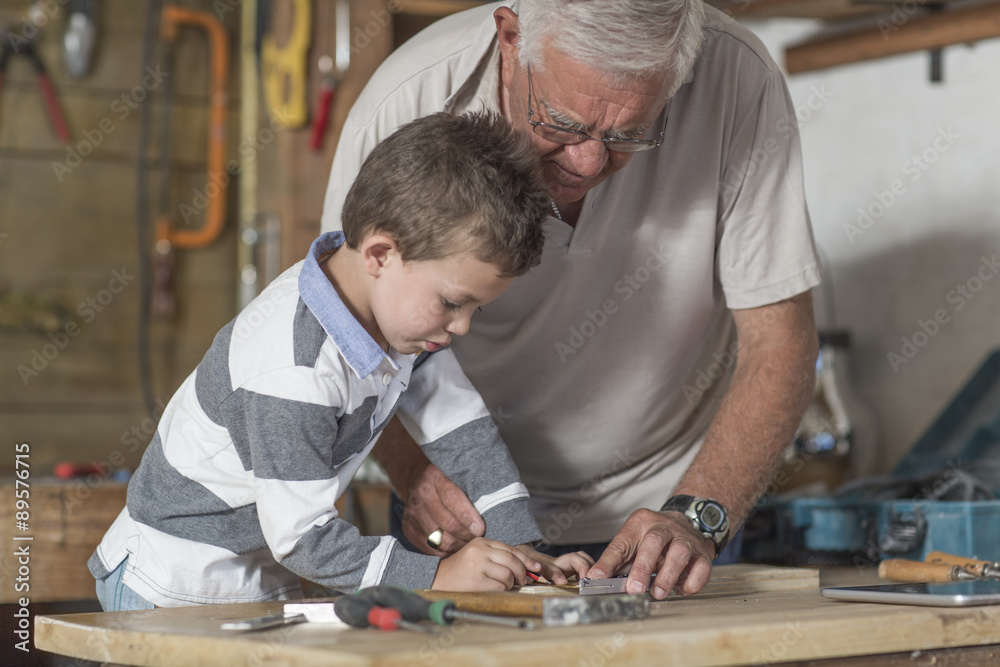 Grandfather and grandson working with wood in a garage Grandfather and grandson working with wood in a garage